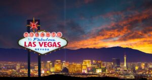 conic 'Welcome to Fabulous Las Vegas' sign illuminated at night, set against a vibrant sunset sky and the glowing Las Vegas skyline, symbolizing the excitement of Vegas Cannabis Week