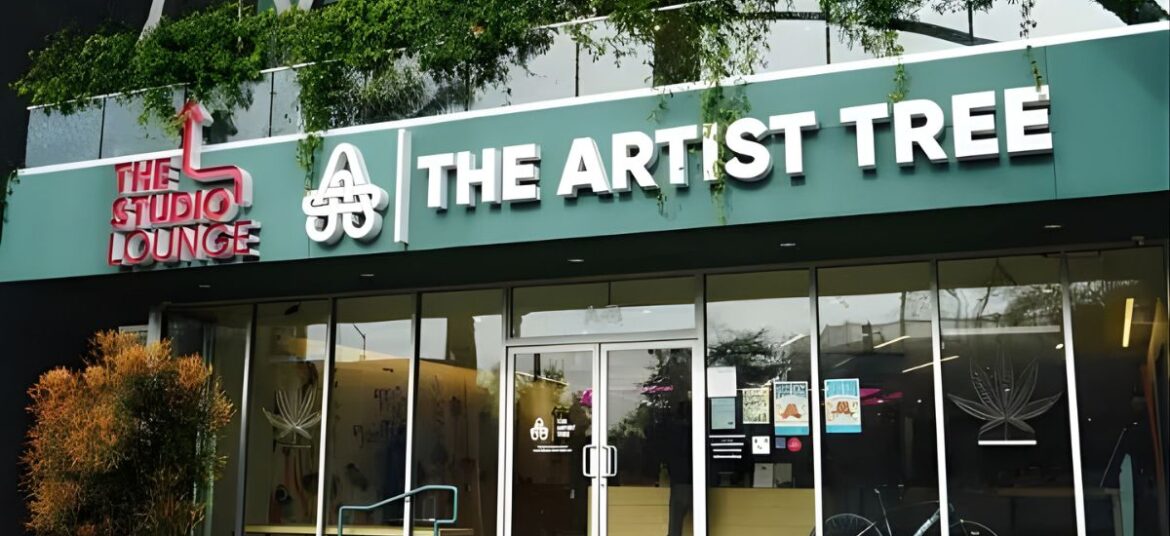 Exterior of The Artist Tree cannabis lounge in WeHo, featuring modern architecture with large glass windows, vibrant greenery, and bold signage for The Studio Lounge and The Artist Tree
