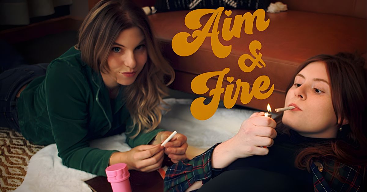 Two women in a cozy indoor setting, one lighting a joint with a lighter and the other preparing cannabis on a shaggy white rug, with the retro-styled text 'Aim & Fire' in golden-yellow overlaid in the upper right corner