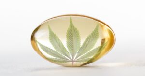 Close-up of a translucent amber capsule containing a green cannabis leaf, set against a plain white background. The image symbolizes the potential inclusion of CBD products in Medicare coverage, highlighting the intersection of cannabis and healthcare.