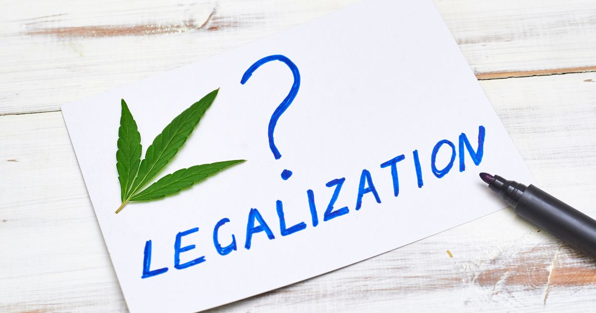 White paper on a rustic wooden surface featuring a green cannabis leaf, a large blue question mark, and the word 'LEGALIZATION' in blue, symbolizing the uncertainty around Florida's recreational marijuana initiative