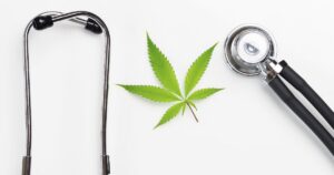 Flat lay of a vibrant green cannabis leaf centered on a white background, framed by a stethoscope with metallic silver and black components. The composition symbolizes the integration of Florida medical marijuana into healthcare discussions.