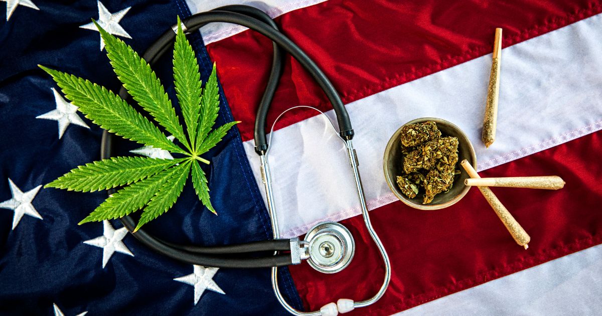 Still life image featuring a green cannabis leaf, a stethoscope, dried cannabis buds in a bowl, and pre-rolled joints arranged on an American flag. The composition symbolizes the use of cannabis for managing Substance Use Disorder and pain relief among veterans
