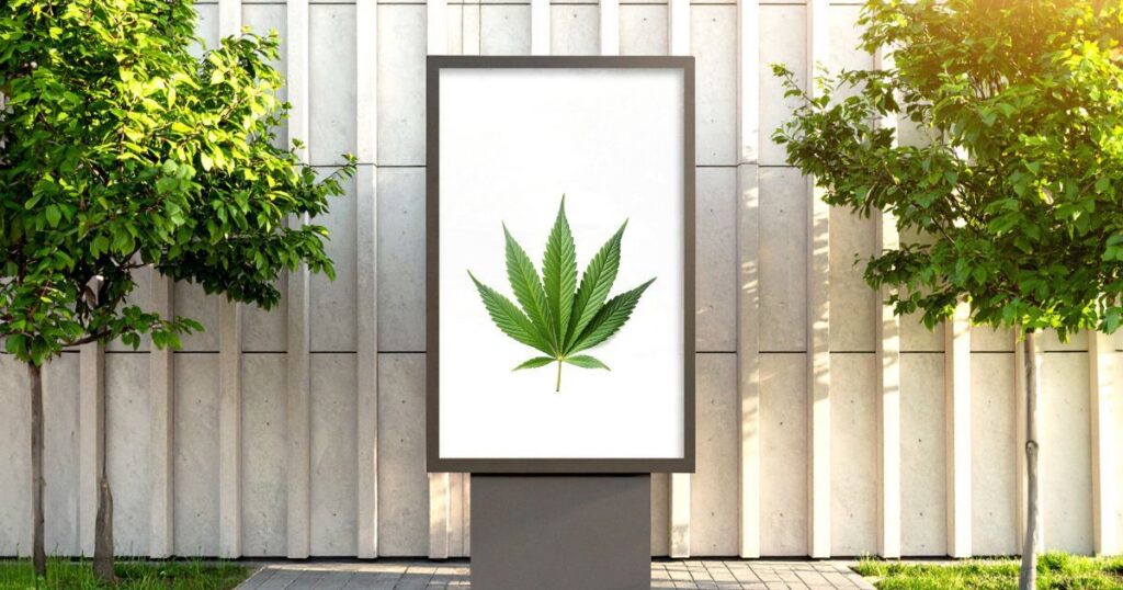Outdoor billboard featuring a vibrant green cannabis leaf on a white background, flanked by small trees and set against a modern building facade. The clean, minimalist design highlights a cannabis marketing strategy focused on simplicity and visibility