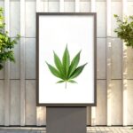 Outdoor billboard featuring a vibrant green cannabis leaf on a white background, flanked by small trees and set against a modern building facade. The clean, minimalist design highlights a cannabis marketing strategy focused on simplicity and visibility