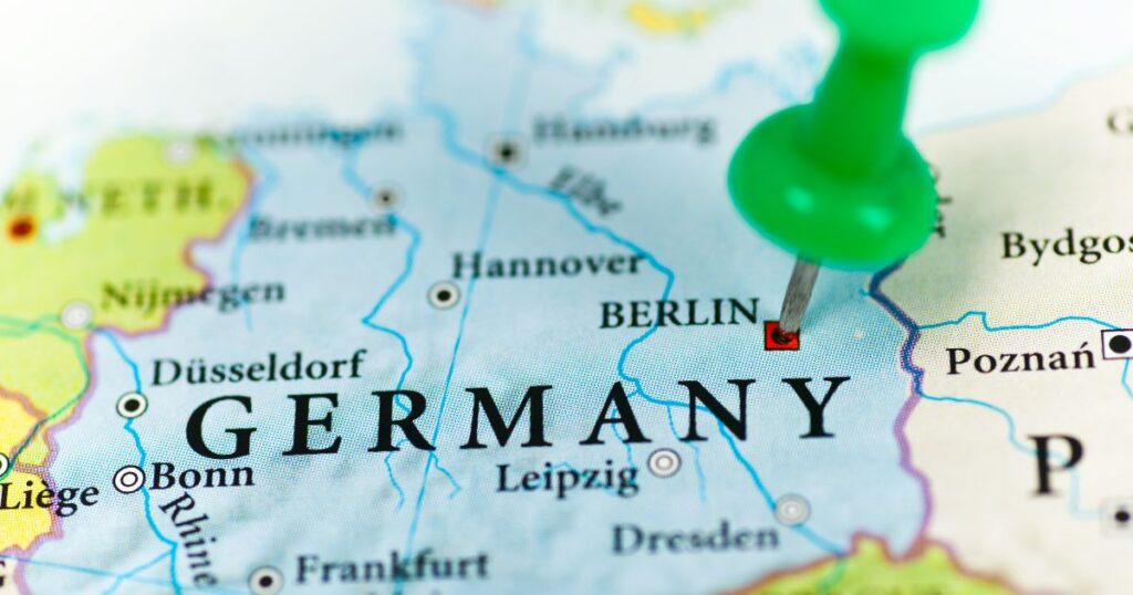 Close-up of a political map highlighting Germany, with a green pushpin marking Berlin. The map displays major cities like Düsseldorf, Frankfurt, and Leipzig, along with rivers like the Rhine and Elbe. The pushpin signifies Berlin as the focal point, representing the German medical cannabis advertising ban. Surrounding countries and borders are also visible for context.