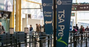 Blue signs and barriers mark a bright TSA PreCheck security entrance where travelers navigate TSA medical marijuana rules.