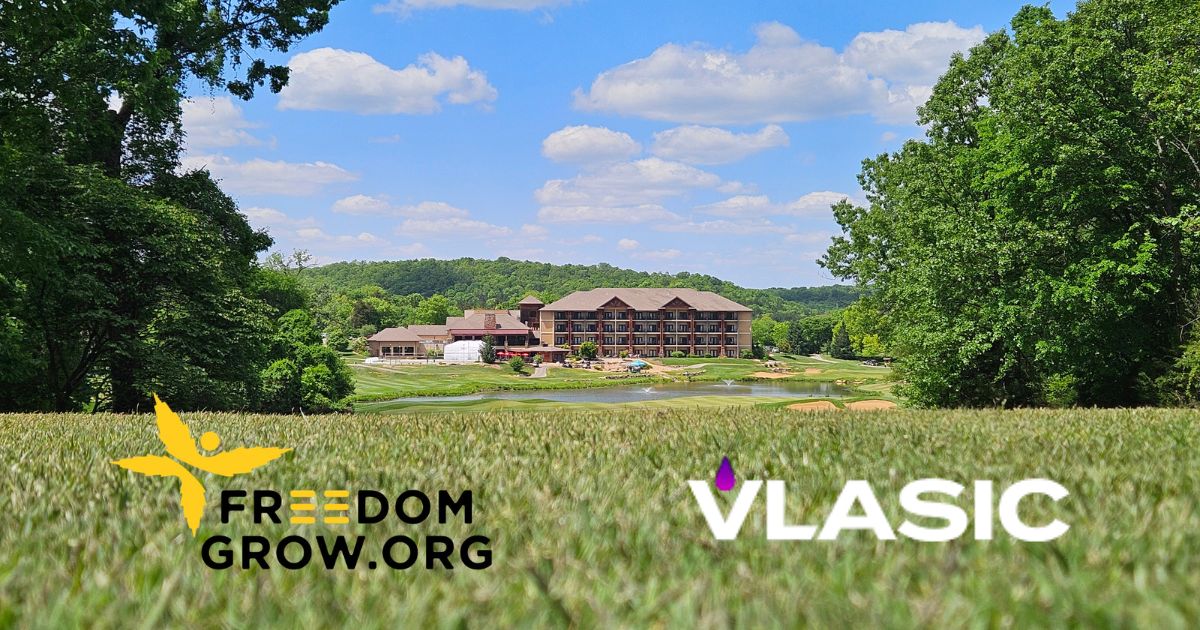 Scenic resort and golf course surrounded by trees and rolling hills under a bright blue sky, with Freedom Grow and Vlasic logos overlaid on the foreground to promote the Vlasic Classic