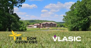 Scenic resort and golf course surrounded by trees and rolling hills under a bright blue sky, with Freedom Grow and Vlasic logos overlaid on the foreground to promote the Vlasic Classic