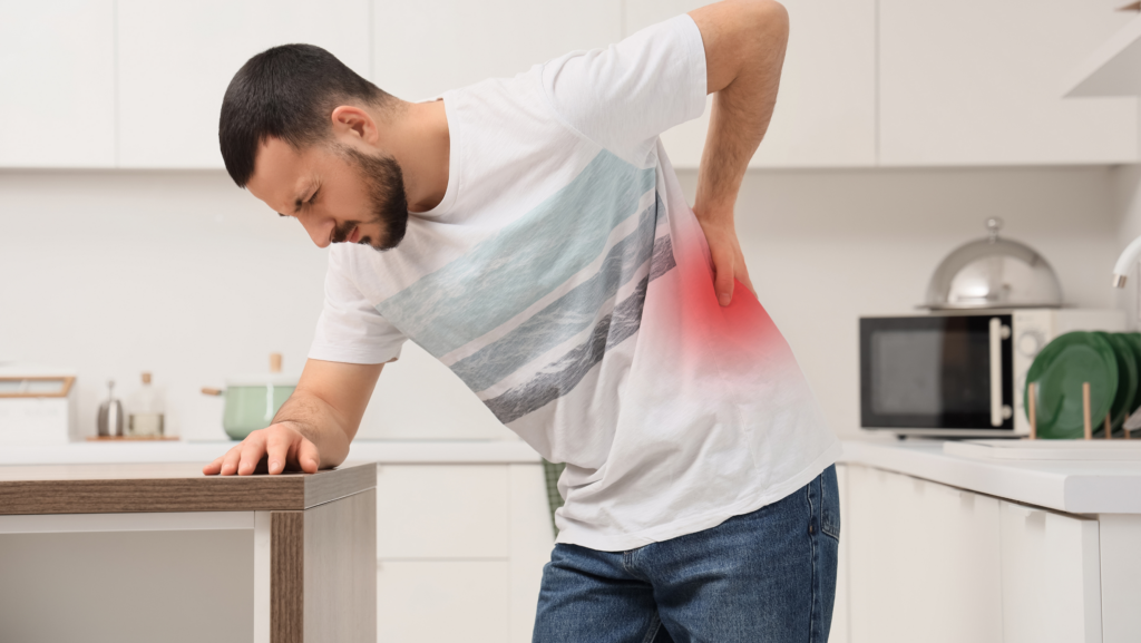 A man bending over with back pain in the kitchen.