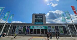 Entrance to Messe Berlin decorated with large event banners, sponsor signage, and flags for Mary Jane Berlin 2026, with visitors walking across the plaza under a bright blue sky.